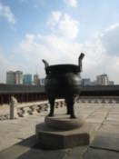 An old incense burner with modern Seoul in the background